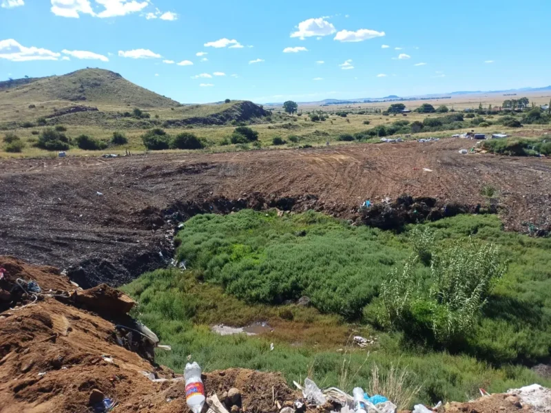 The Burgersdorp landfill site, with waste spread over cleared ground next to open veld.